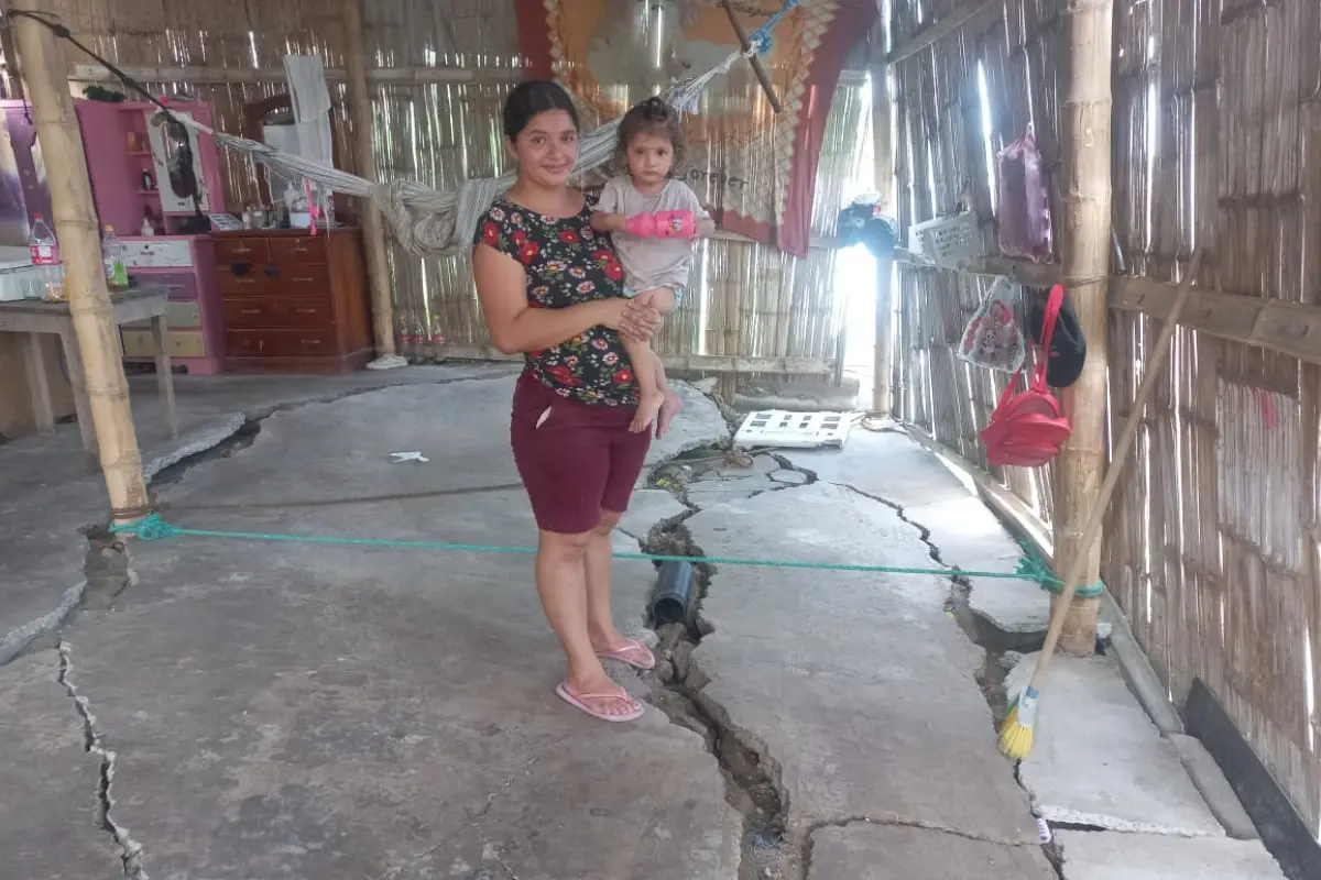 Gema Zambrano carga a su hija menor en medio de su casa, donde el cemento del piso se ha partido por el hundimiento de tierra.