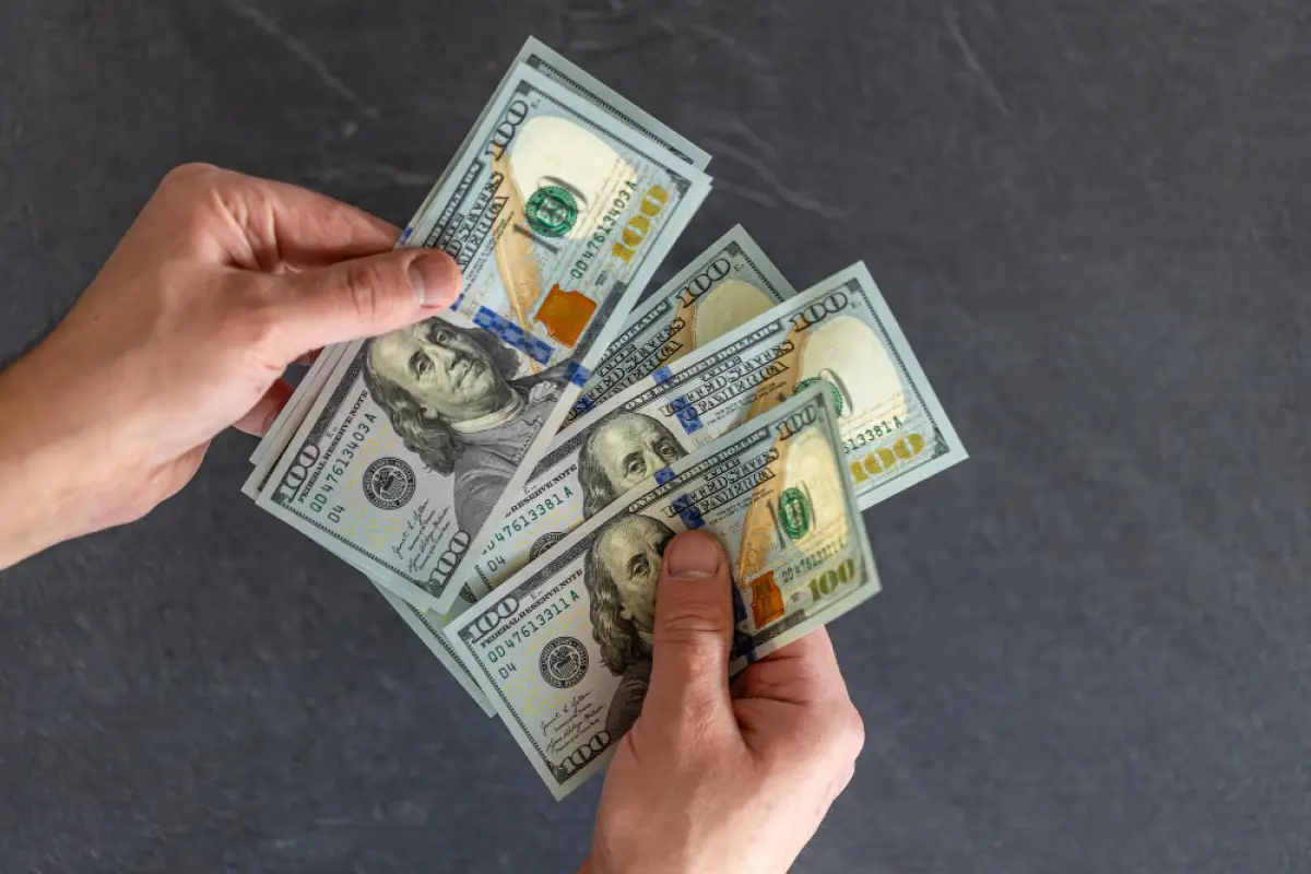 Pago del décimo tercer sueldo en Ecuador 2025, billetes de cien dólares.