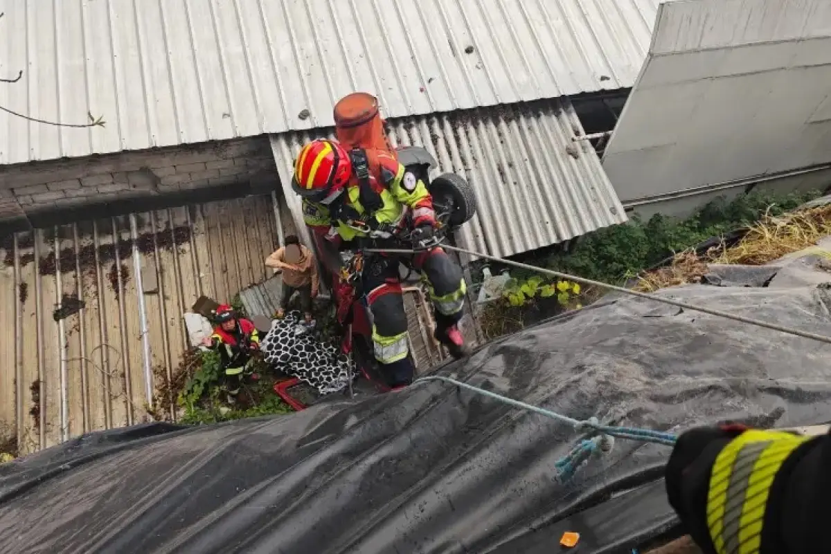 El auto rodó desde una altura de cinco metros y cayó sobre el techo de una vivienda. (Foto Bomberos Quito)