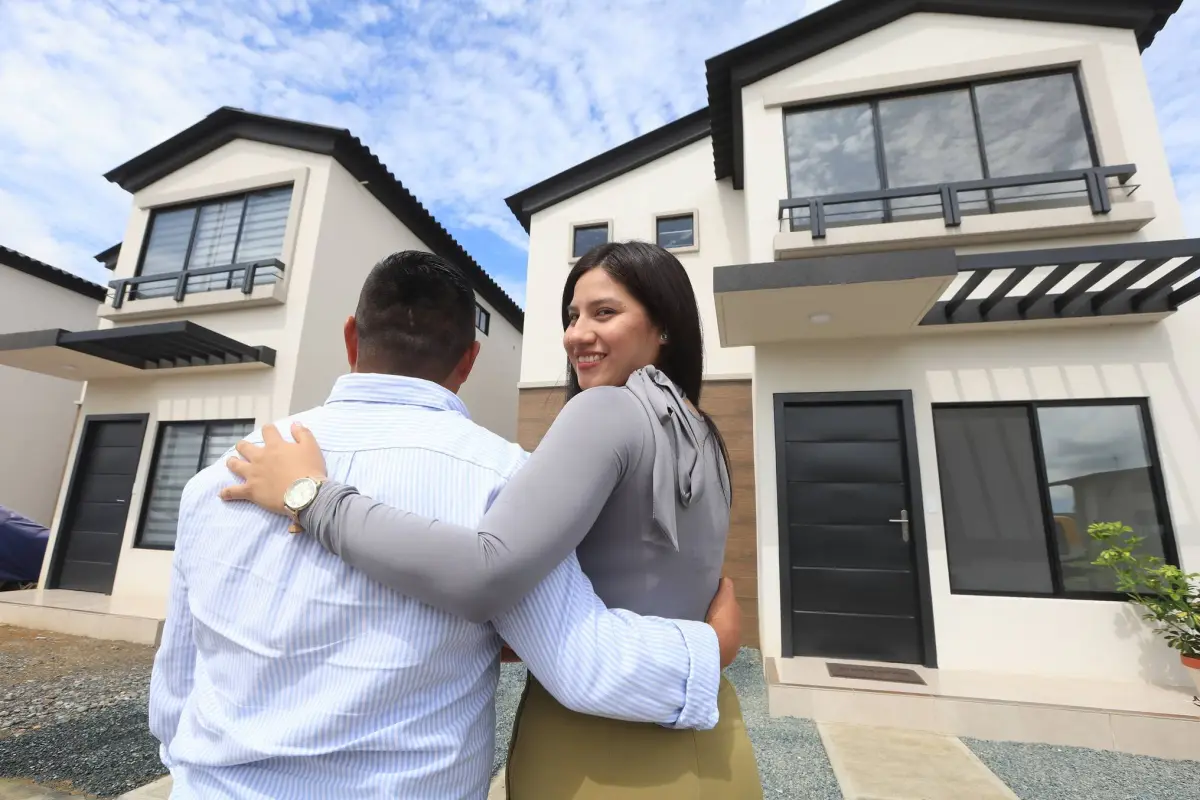 Familia ecuatoriana frente a vivienda de interés social beneficiada por créditos hipotecarios de 30 años