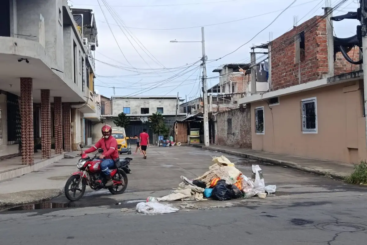 Un motorizado circula junto a un montículo de basura en la Calle 119 y avenida 104, en Los Esteros., El Diario