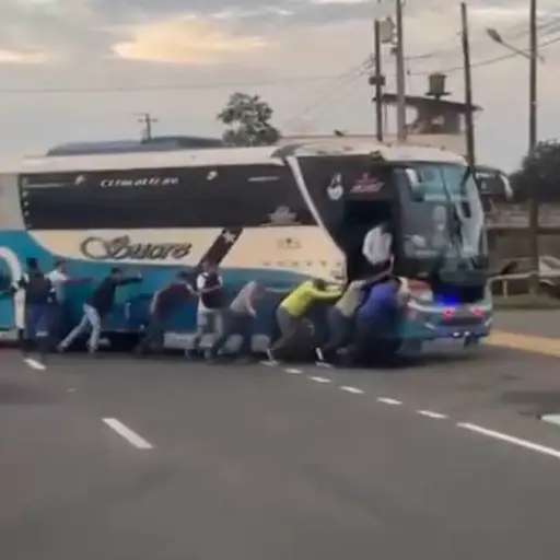 Pasajeros empujan un bus interprovincial hasta una gasolinera en la vía Santo Domingo-Quevedo