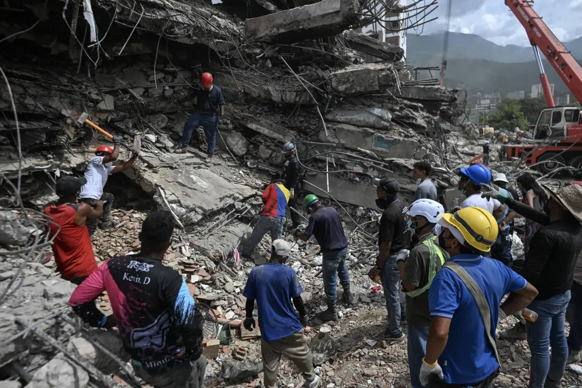 Voluntarios y equipos de rescate buscan cuerpos entre los escombros de un edificio derrumbado en Caraballeda, Venezuela, el 23 de julio de 2026, casi un mes después de los terremotos del 24 de junio., JUAN BARRETO / AFP