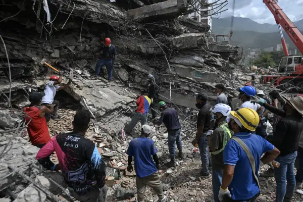 Voluntarios y equipos de rescate buscan cuerpos entre los escombros de un edificio derrumbado en Caraballeda, Venezuela, el 23 de julio de 2026, casi un mes después de los terremotos del 24 de junio. ,JUAN BARRETO / AFP
