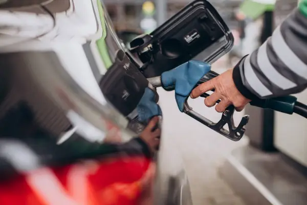 hombre tanqueando gasolina en estación de servicio